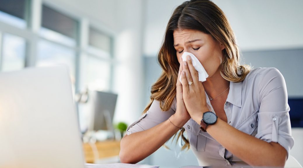 Sneezing into tissue. Cropped shot of a businesswoman working in her office while suffering from allergies